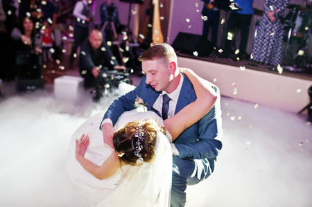 Newly married couple dancing on their wedding party with heavy smoke and multicolored lights on the background.の写真素材