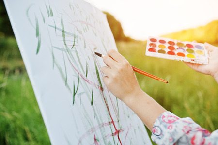 Close-up photo of female hand painting on the paper with watercolors.の写真素材