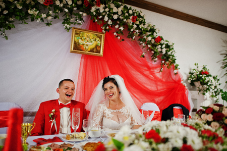 Gorgeous wedding couple sitiing at the table and laughing on theirr wedding day.の写真素材