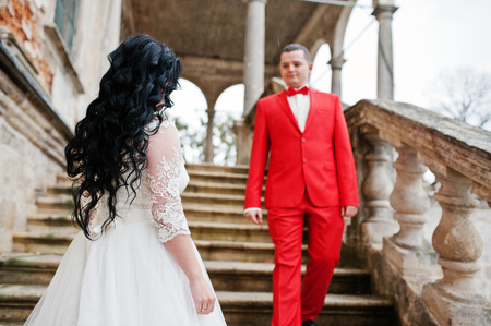 Awesome newly married couple enjoying each other's company on the stairs of old castle on a rainy wedding day.の写真素材