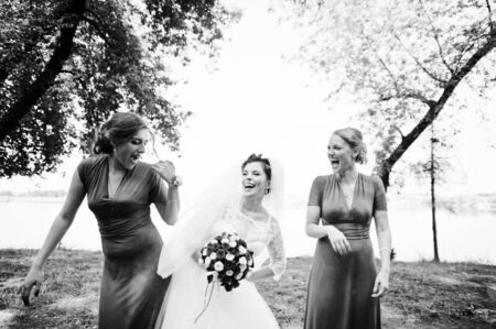 Gentle bride and beautiful bridesmaids are having great fun in the park on a sunny wedding day. Black and white photo.の写真素材
