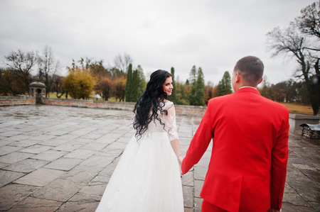 Beautiful wedding couple walking on the pavement on a rainy and cloudy day.の写真素材