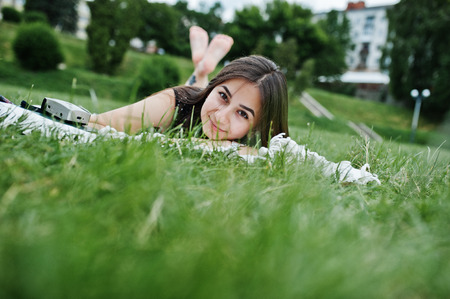 Portrait of a gorgeous woman in black polka dot dress laying next to the books on the blanket on the grass in the park.の写真素材