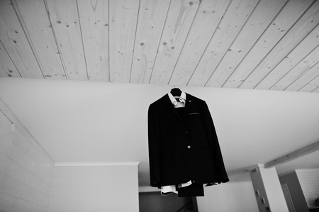 Groom's wedding suit hanging on the rack in big light room. Black and white photo.の写真素材
