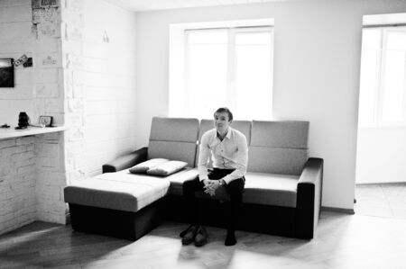 Portrait of a handsome groom dressing up and getting ready for his wedding. Black and white photo.の写真素材