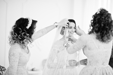 Bridesmaids and mother helping bride to dress up and get ready for her wedding. Black and white photo.の写真素材