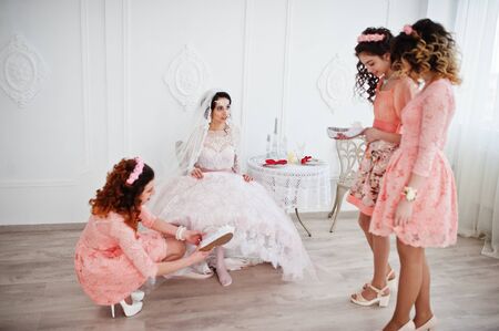 Bridesmaids helping bride to put her wedding shoes on and get ready for her wedding.の写真素材