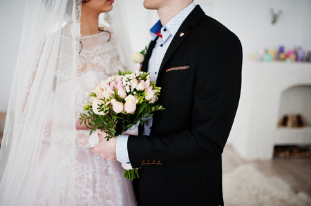 Beautiful wedding couple kissing and looking into each other's eyes in the studio.