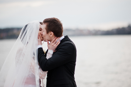 Close-up photo of a kissing wedding couple on the lakeside.の写真素材