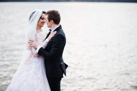 Newly married couple walking and posing on the lakeside on their wedding day.の写真素材