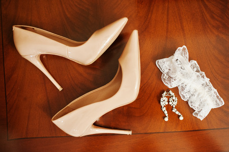 Close-up photo of bridal high heels, earrings and garter laying on the table.の写真素材