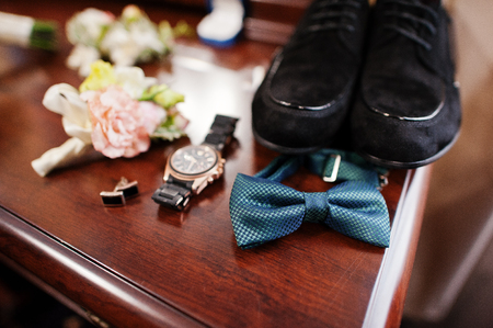 Close-up photo of groom's wedding shoes, bow tie, watch, cufflinks and buttonhole flowers.の写真素材