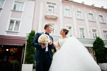 Newlyweds walking on the street of an old town with cafe and flowers on it on a wedding day.の写真素材