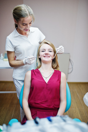 Gorgeous young female dentist checking her patient's teeth up in a specially-equipped cabinet.の写真素材