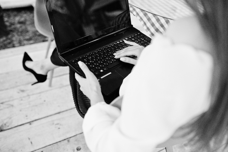 Portrait of a strong independent successful businesswoman wearing smart casual clothing and glasses working on a laptop in a cafe.の写真素材