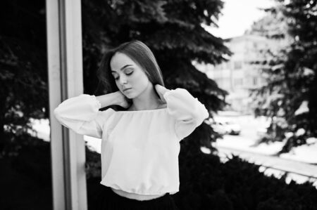 Portrait of an amazing woman in white blouse and wide black pants posing with pine trees on the background. Black and white photo.の写真素材