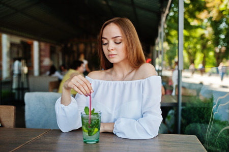 Portrait of a stunning young woman posing with mojito cocktail in cafe next to the park.の写真素材