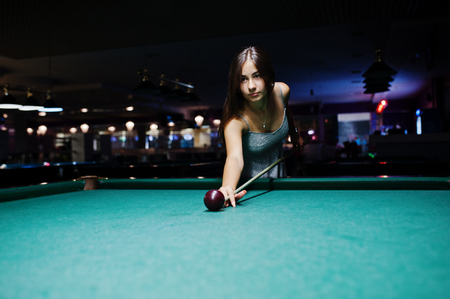 Portrait of an attractive young woman in dress playing pool.の写真素材