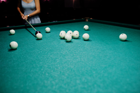 Woman in dress playing pool with a man in a pub.の写真素材