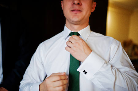 Portrait of a good-looking groom dressing up for his wedding.の写真素材