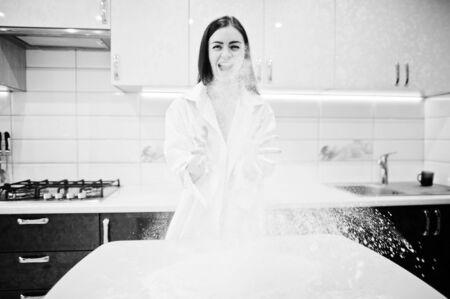Brunette girl, wear at shirt and underwear play with flour at the white kitchen.の写真素材