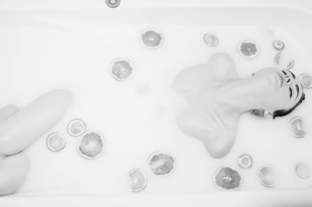 Sexy brunette girl at the bathroom with milk and fruits. Youth bath for body.