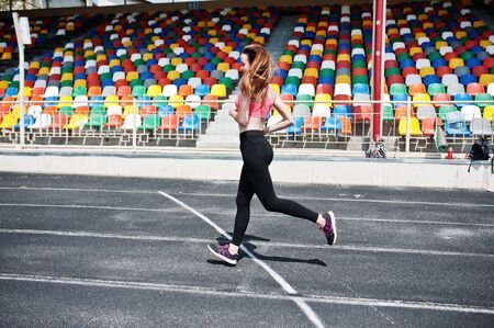 Fitness sporty girl in sportswear at stadium. Happy sexy woman running on athletic track in stadium.の写真素材