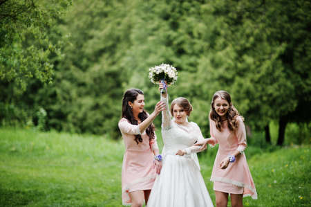 Attractive bride posing and having fun with two her bridesmaids in the park on a sunny spring wedding day.の写真素材