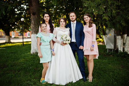 Wedding couple posing with two bridesmaids in pink dresses and a girl in blue short dress outdoor.の写真素材