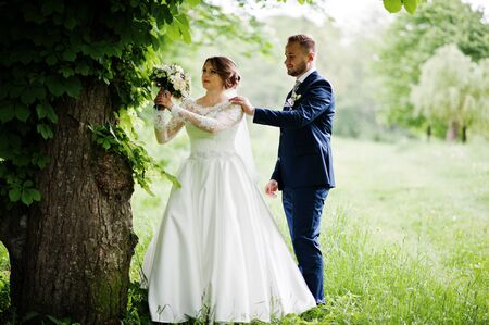 Amazing wedding couple walking and posing somewhere in the green meadow in spring.の写真素材