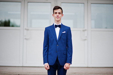 Portrait of a handsome high school graduate in stylish tuxedo posing on the stairs on the prom.の写真素材