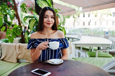 Gorgeous brunette girl sitting on the table in cafe with cup of coffee.の写真素材