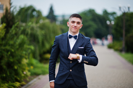 Portrait of a handsome young man in formal fancy suit posing on the pavement in the park on a prom day.の写真素材