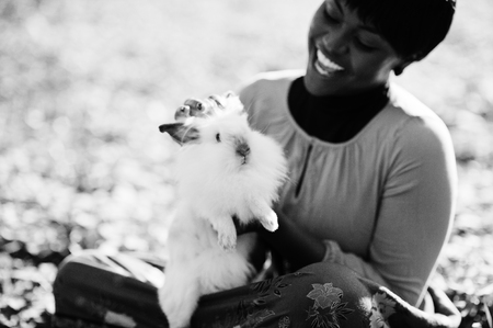 African american girl at yellow and red dress with white rabbit at hands.の写真素材