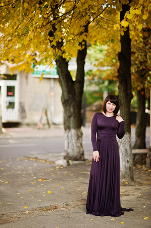 Adult brunette woman at violet gown on autumn fall background.の写真素材