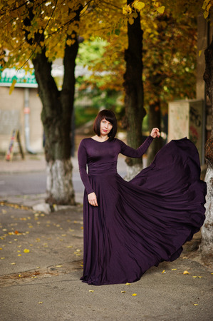 Adult brunette woman at violet gown on autumn fall background.の写真素材