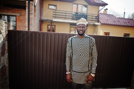 Portrait of stylish black african american man at hat and sunglasses against fence.の写真素材