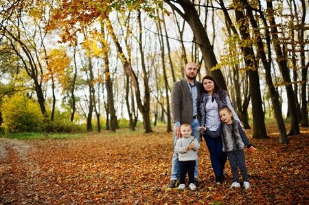 Happy caucasian family of mom dad and little girl with boy at majestic autumn fall forest.の写真素材
