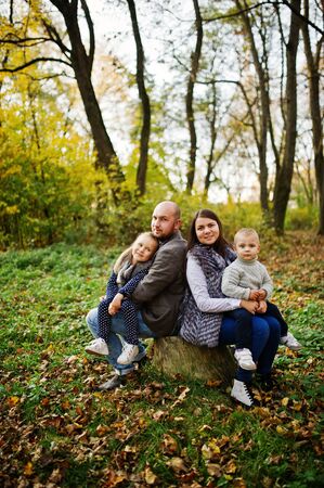 Happy caucasian family of mom dad and little girl with boy at majestic autumn fall forest.の写真素材