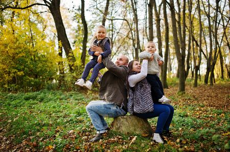 Happy caucasian family of mom dad and little girl with boy at majestic autumn fall forest.の写真素材