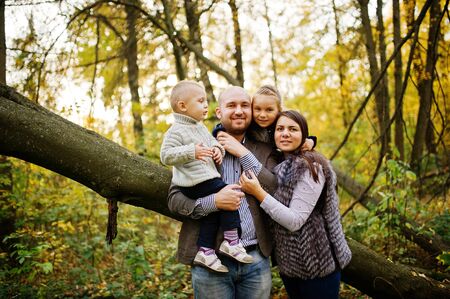 Happy caucasian family of mom dad and little girl with boy at majestic autumn fall forest.の写真素材