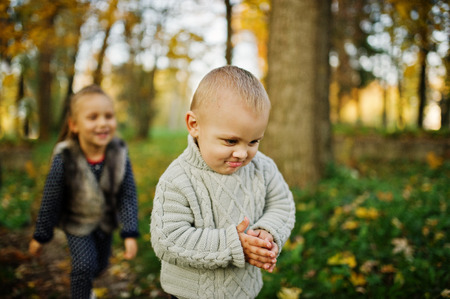 Little girl with boy at majestic autumn fall forest. Sister with brother, love of childrens.の写真素材