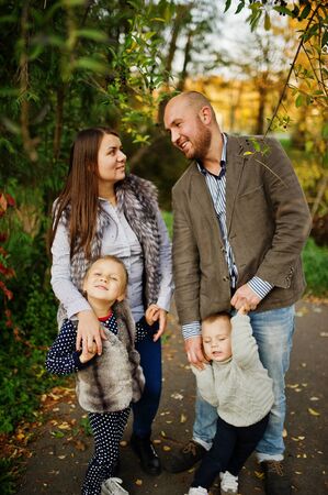 Happy caucasian family of mom dad and little girl with boy at majestic autumn fall forest.
