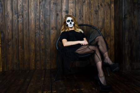 Halloween skull make up girl wear in black against wooden wall at studio.の写真素材