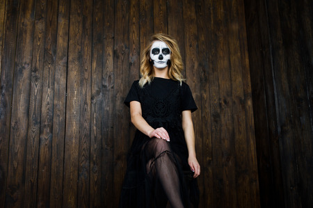 Halloween skull make up girl wear in black against wooden wall at studio.の写真素材