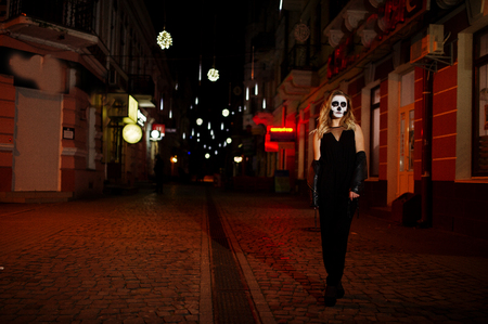 Halloween skull make up girl wear in black at night street of city.の写真素材