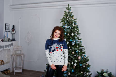 Girl wear warm sweater background new year tree on studio. Happy winter holidays concept.の写真素材