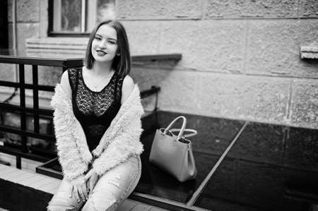 Red haired girl with red handbag posed at street of city.の写真素材