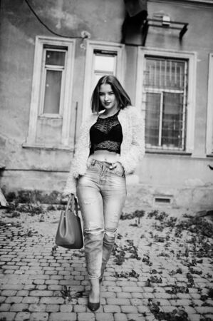 Red haired girl with red handbag posed at street of city.の写真素材