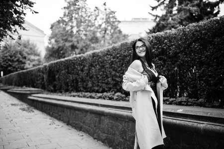 Black hair sexy woman in glasses and coat posed on street.の写真素材